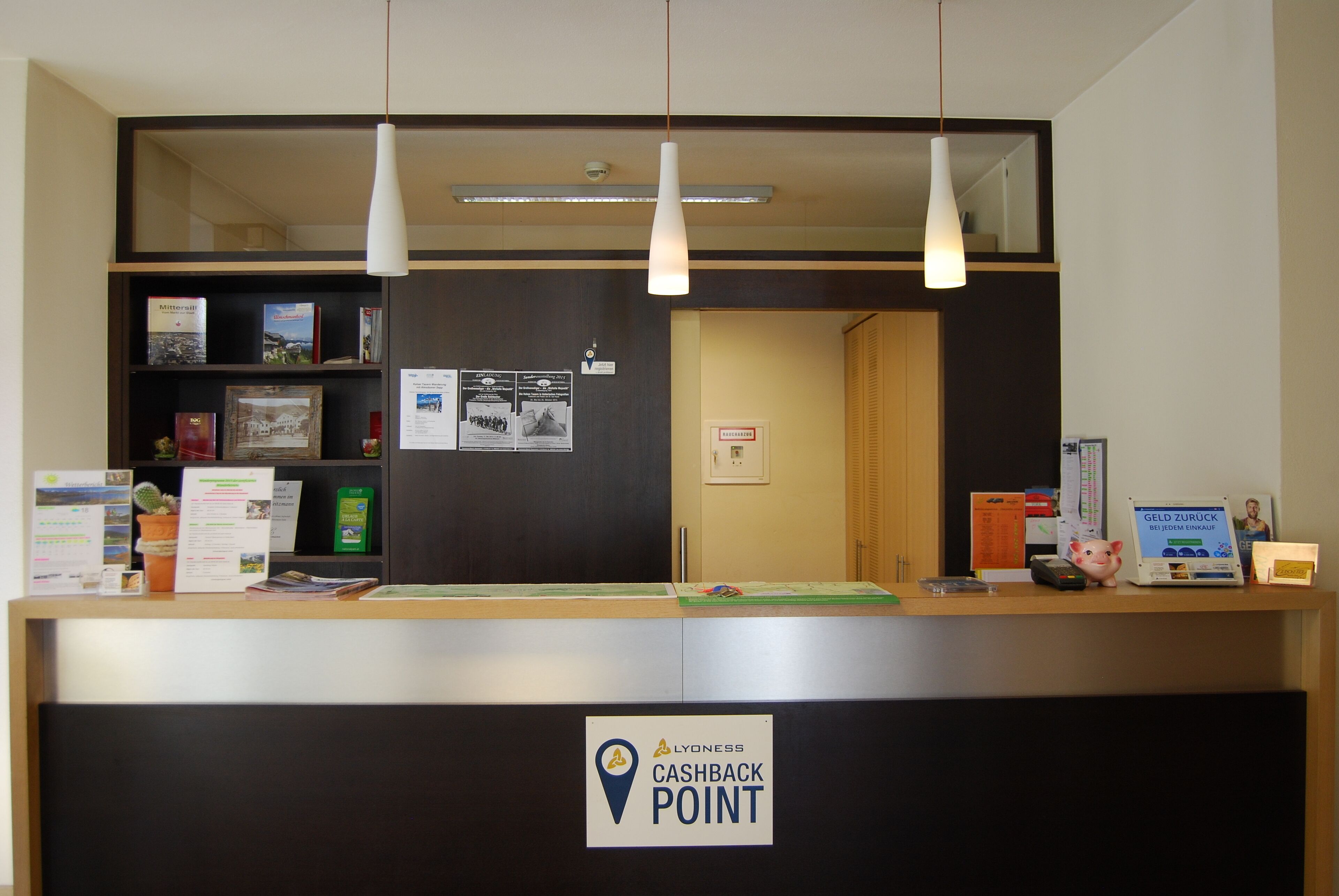 A reception desk with a 'Cashback Point' sign, a bulletin board with notices, and a counter with various items.