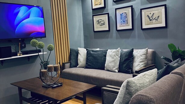 Ein modernes Wohnzimmer mit grauem Sofa, einem Couchtisch und einem Flachbildfernseher.