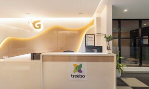A reception desk with a 'treebo' logo, a 'G' sign, and a Dell computer. - Treebo Global Orchid (Mysore)
