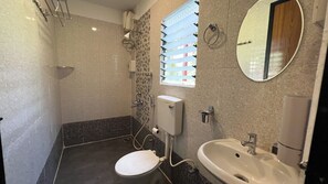 Ein Badezimmer mit Toilette, Waschbecken, Dusche und Spiegel.