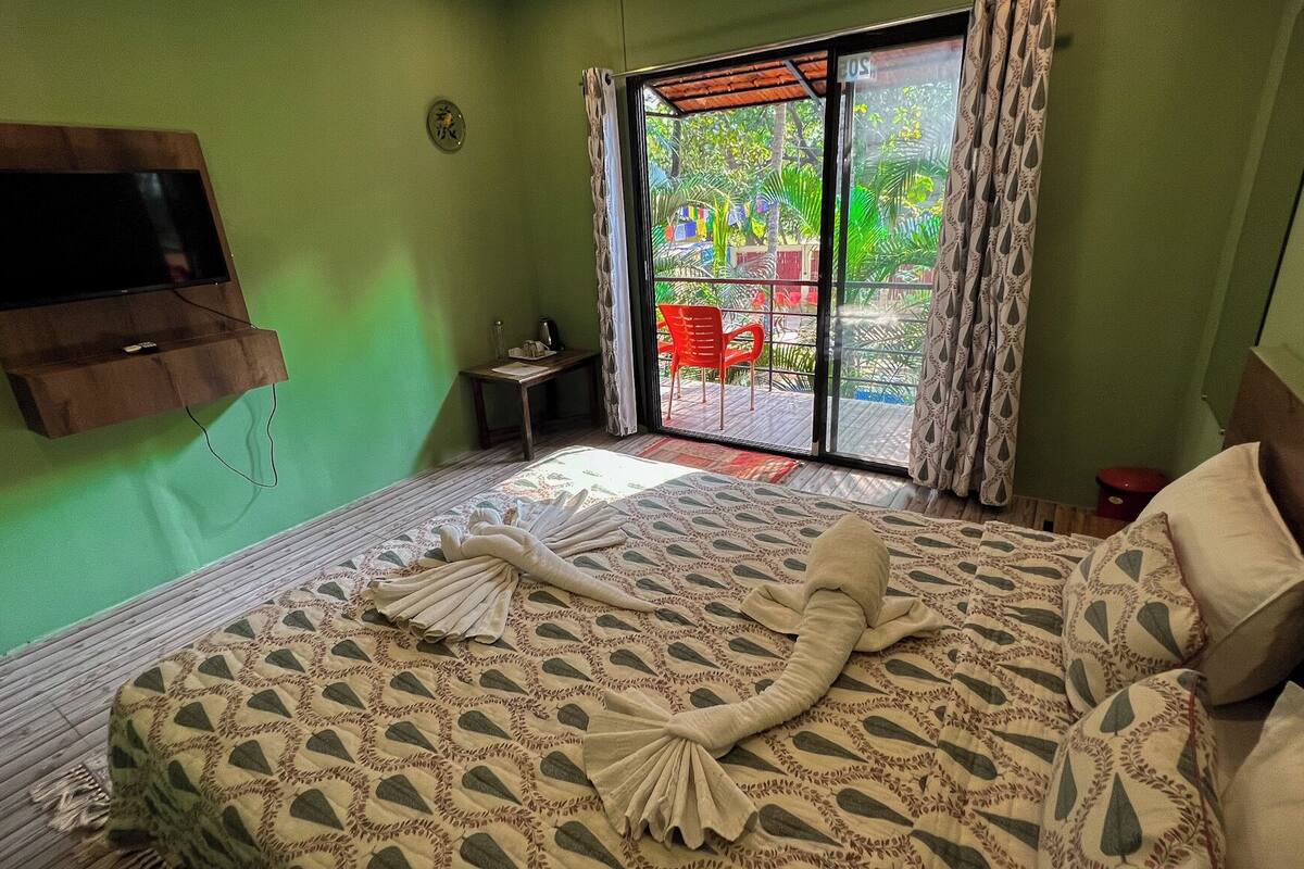 A room with a bed, a television mounted on the wall, and a window with curtains.