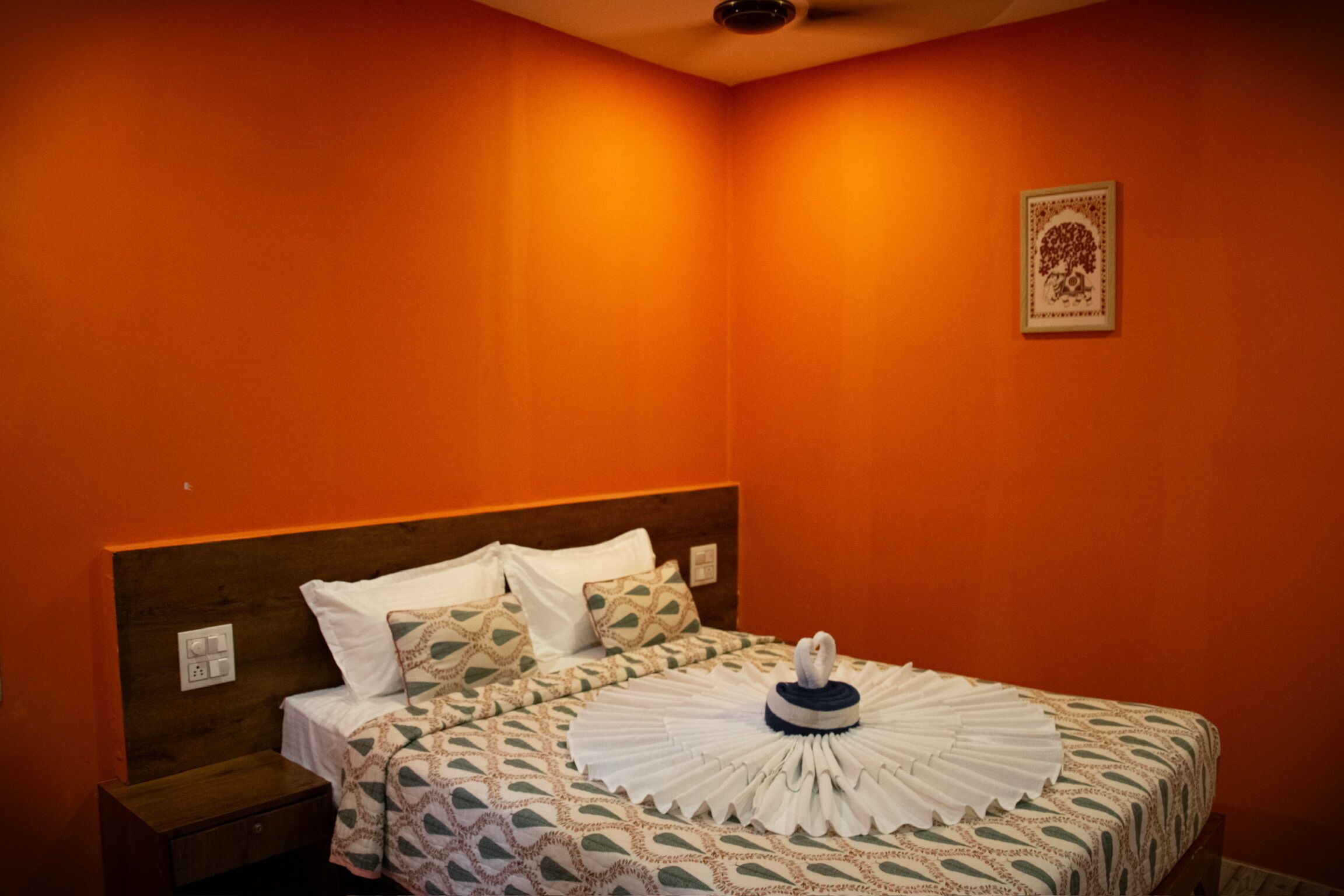 Ein Hotelzimmer mit einem Bett, einem Nachttisch und einem an der Wand befestigten Lichtschalter.
