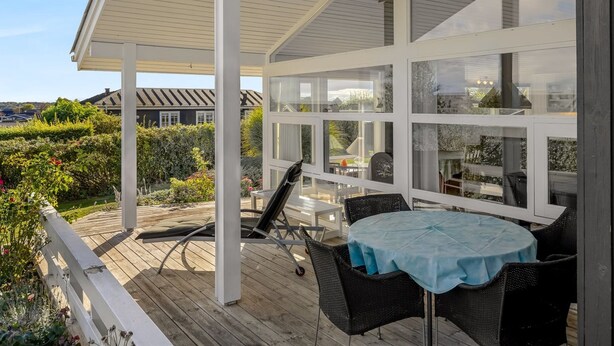 A covered patio with a table and chairs, overlooking a garden and neighboring houses. - "Tjarven" - 350m from the sea by Interhome (Hejls)