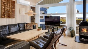 A modern living room with a black leather sofa, a wooden coffee table, a flat-screen TV, and a wood-burning stove. - "Tjarven" - 350m from the sea by Interhome (Hejls)