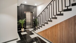 A modern interior with a black and white checkered floor, a wooden wall, and a black railing staircase. - Hotel SK Elite (Jodhpur)