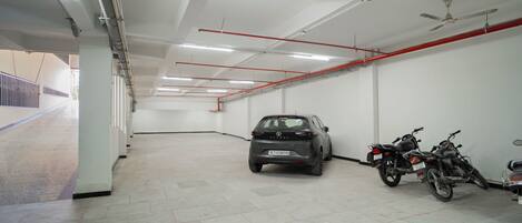 A parking garage with a car and a motorcycle parked.