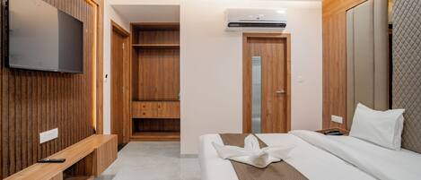 Una habitación de hotel con cama, televisión montada en la pared, armario y equipo de aire acondicionado.
