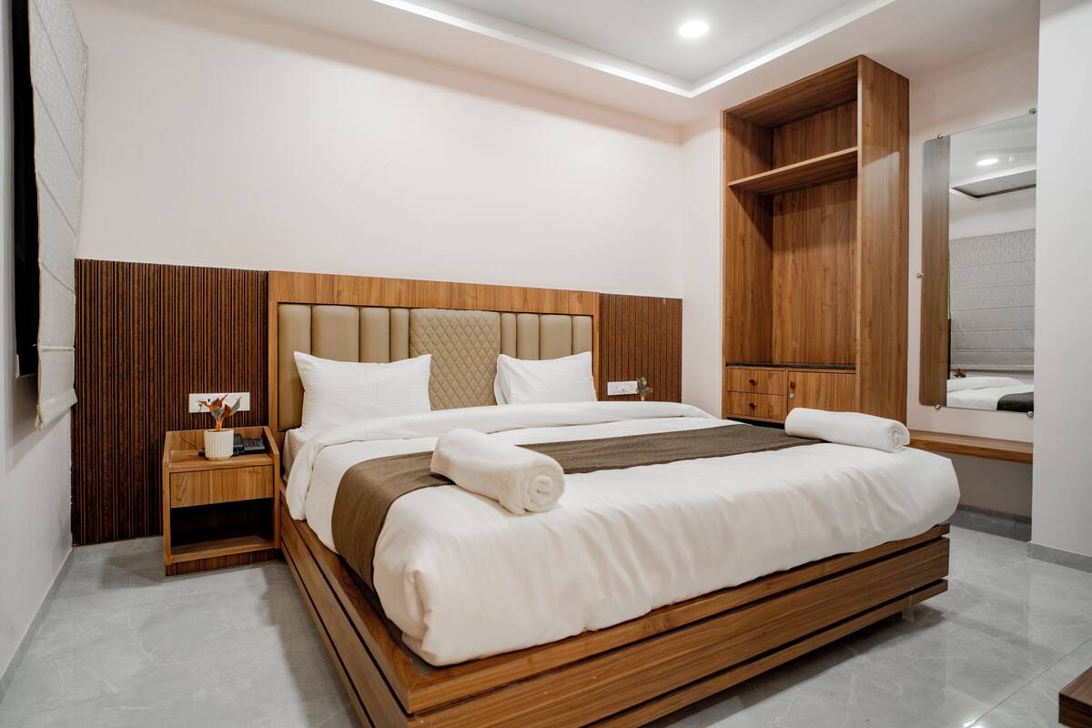 Une chambre à coucher moderne avec un cadre de lit en bois, une table de chevet, une armoire intégrée et un grand miroir.