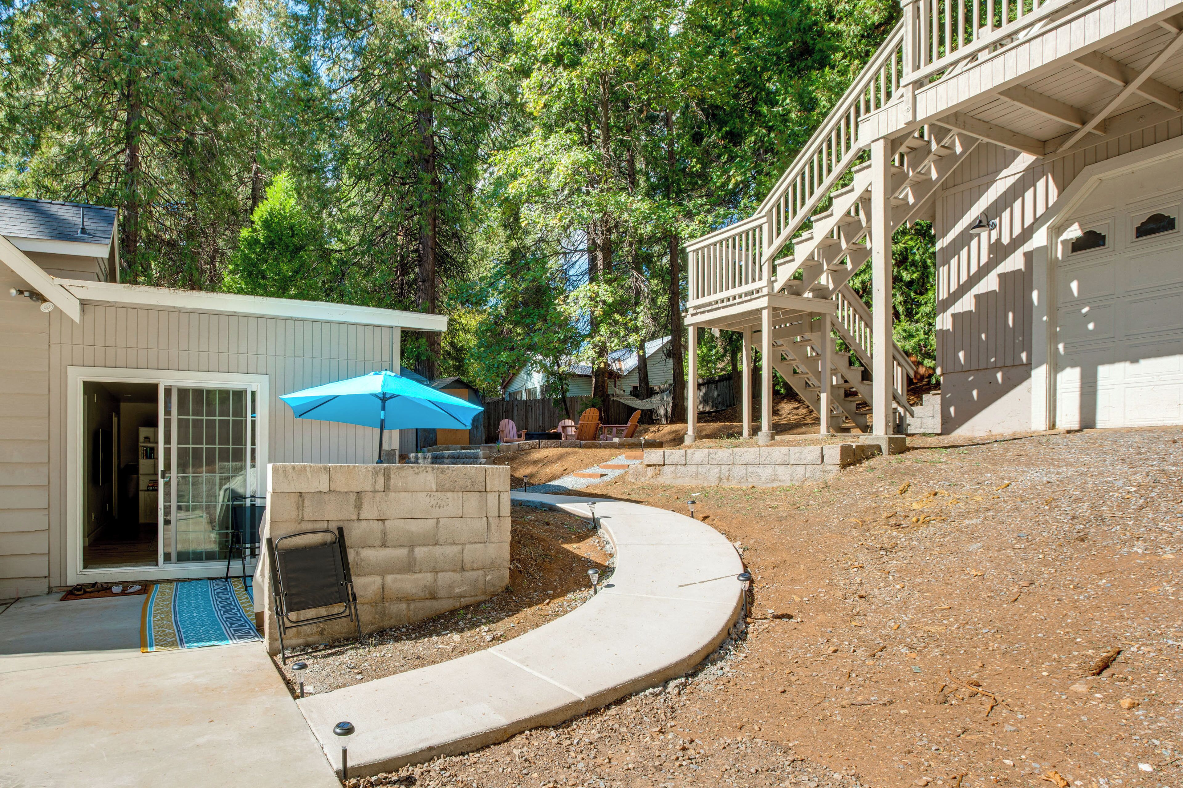 A residential area with a curved driveway, a covered patio, and a staircase leading to a garage.
