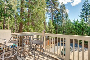 A deck with outdoor furniture and a view of a forested area.