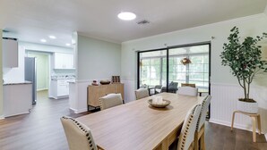 Un comedor amplio con una larga mesa de madera, sillas acolchadas y una planta en maceta.