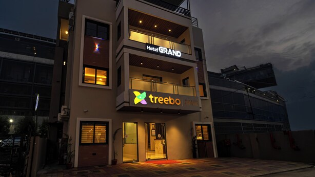 Et moderne hotel med et skilt der siger 'Hotel GRAND', et skilt der siger 'treebo GRAND', samt en balkon med gelændere.