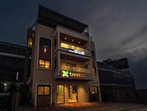 A modern hotel with a 'Hotel GRAND' sign, a 'treebo GRAND' sign, and a balcony with railings. - Treebo Grand (Indore)