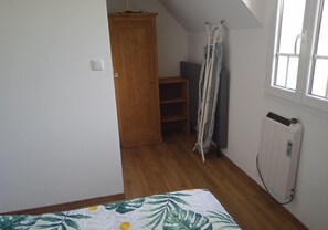 Una habitación con un armario de madera, un radiador y una ventana con cortinas.