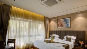 A hotel room with a large bed, a chair, a nightstand, and a painting on the wall. - Lance 21 Premium Serviced Apartments (Chennai)