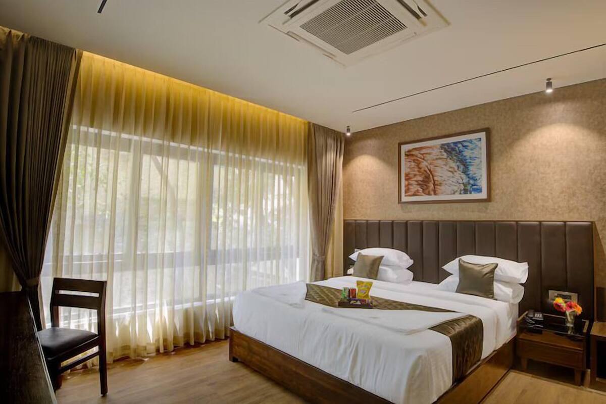 A hotel room with a large bed, a chair, a nightstand, and a painting on the wall.