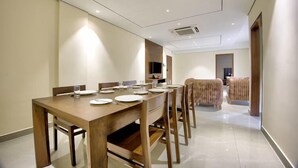 A modern dining area with a long wooden table set for six, surrounded by chairs. - Lance 21 Premium Serviced Apartments (Chennai)