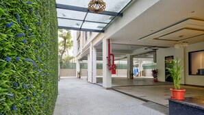 A modern hotel lobby with a glass ceiling, a green wall with blue flowers, and a tiled floor. - Lance 21 Premium Serviced Apartments (Chennai)