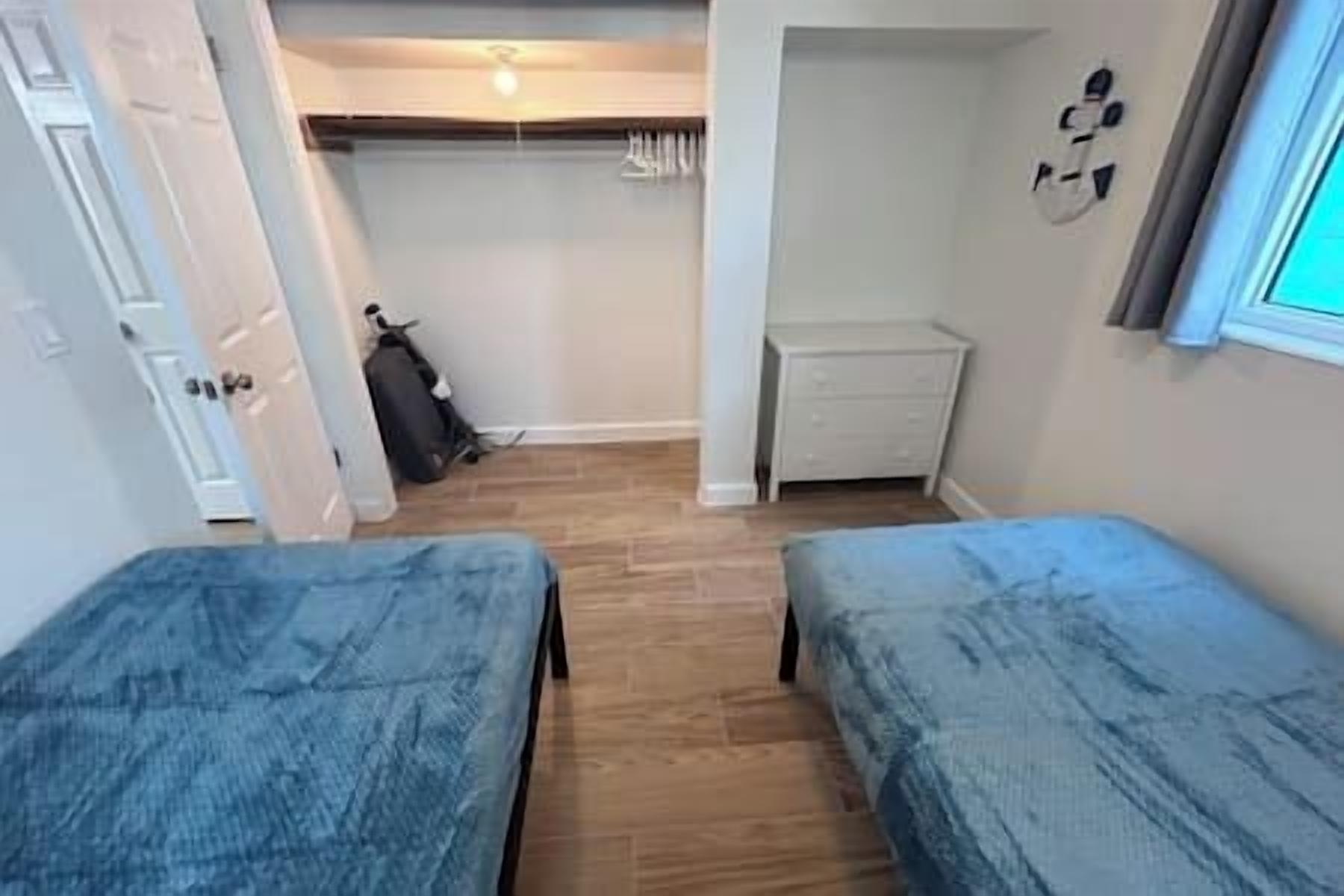 A room with two beds, a wardrobe, and a small desk.