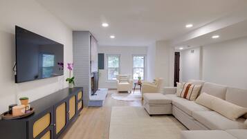 A modern living room with a flat-screen TV, a sofa, a coffee table, and a fireplace.