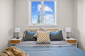 Una camera da letto con un letto, due comodini, una finestra con vista e una coperta sul pavimento.