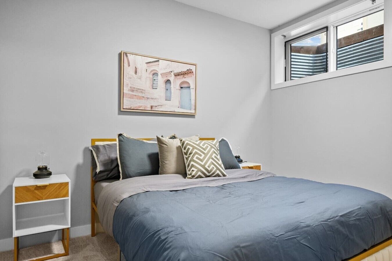 Ein Schlafzimmer mit einem Bett, einem Nachttisch, einem Fenster und einem Wandbild.