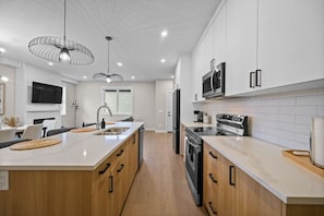 Una cucina moderna con isola centrale, elettrodomestici in acciaio inossidabile e illuminazione a sospensione.