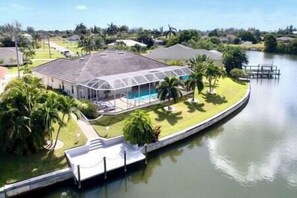 Una casa con piscina, circondata da un canale e palme.