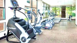 En rad StairMaster-träningsmaskiner i ett väl upplyst gym med stora fönster och en takfläkt.