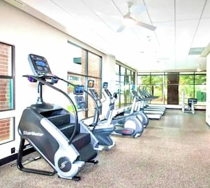 A row of StairMaster treadmills in a well-lit gym with large windows and a ceiling fan. - Luxury In Ga Tech (Atlanta)