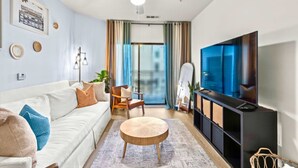 Ett modernt vardagsrum med en vit soffa, ett runt soffbord och en tv som står på ett svart tv-bord.