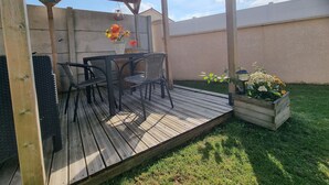 An outdoor patio with a wooden deck, a table with chairs, and a hanging light fixture.