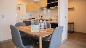 Une cuisine moderne avec des meubles en bois, un plan de travail et une table à manger avec des chaises. Il y a deux bouteilles d’eau sur la table.