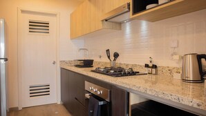 Une cuisine moderne avec des meubles en bois, un plan de travail en granit, des appareils électroménagers en acier inoxydable et une machine à café.