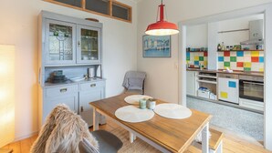 Una cocina moderna con una mesa de madera, una lámpara colgante roja y un salpicadero colorido.