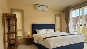 A hotel room with a large bed, a wooden ladder, a nightstand with a lamp, and an air conditioning unit on the wall. - Kata Kata Stay (Karon)
