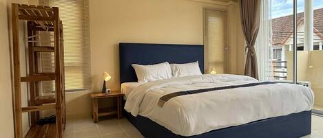 Una habitación de hotel con una cama grande, una escalera de madera, una mesita de noche con una lámpara y un equipo de aire acondicionado en la pared.
