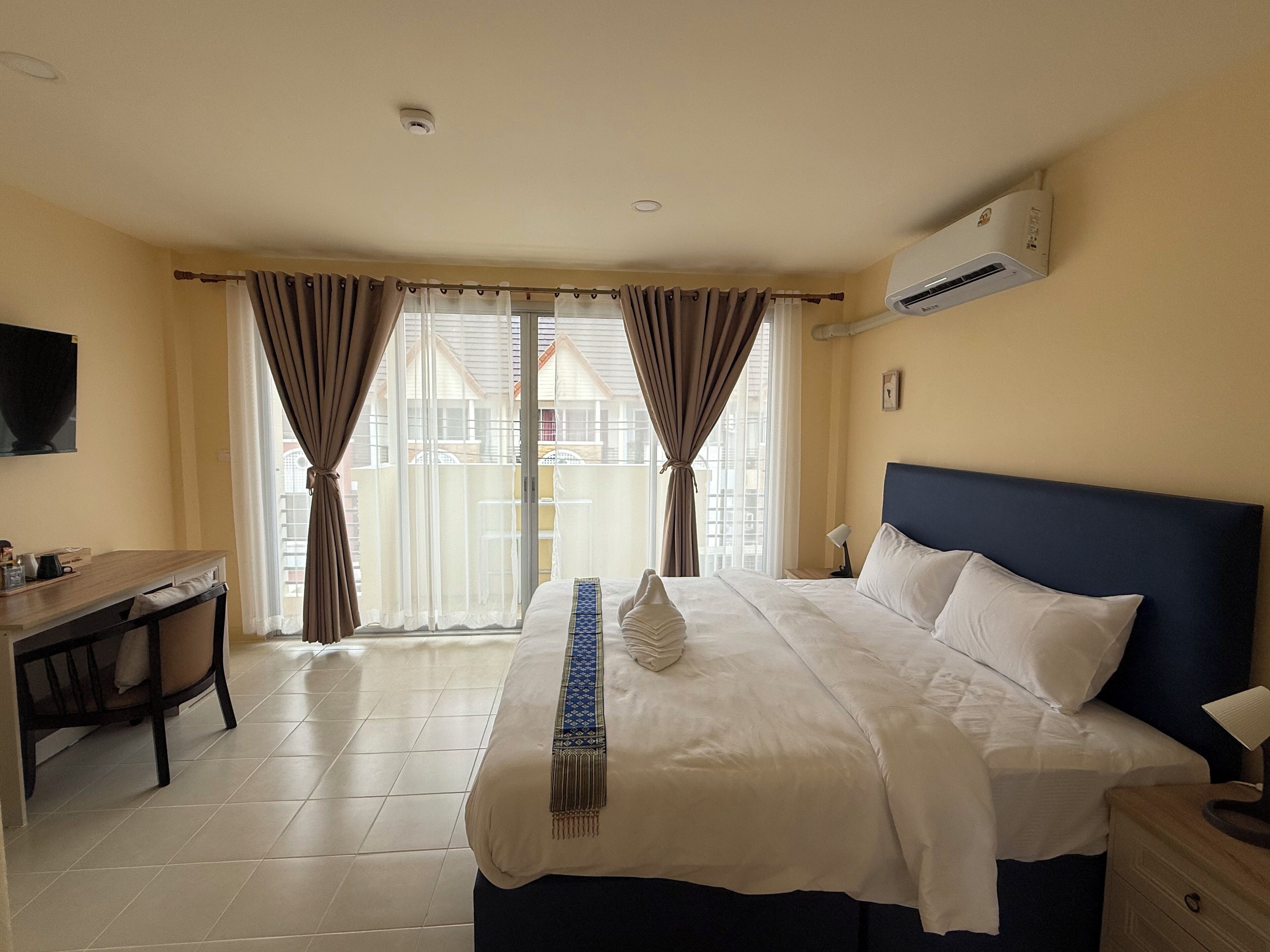 Une chambre d’hôtel équipée d’un lit, d’un bureau, d’une chaise, d’une télévision et d’un appareil de climatisation.