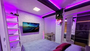 A modern bedroom with a bed, a TV on the wall, a desk, and a chair. - White Pearl Exclusive Apartment (Roma)