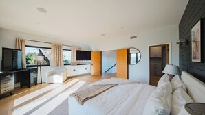 Un dormitorio moderno con una cama grande, un escritorio, un televisor y vistas al exterior.