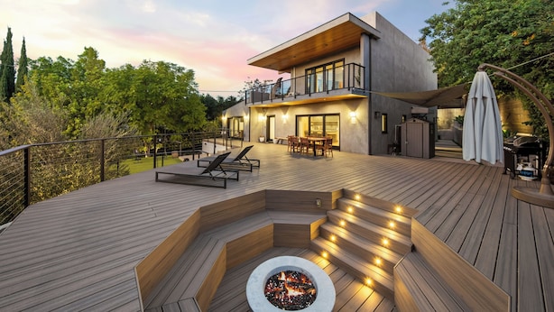 Una casa moderna con terraza, asientos exteriores y un pozo de fuego.