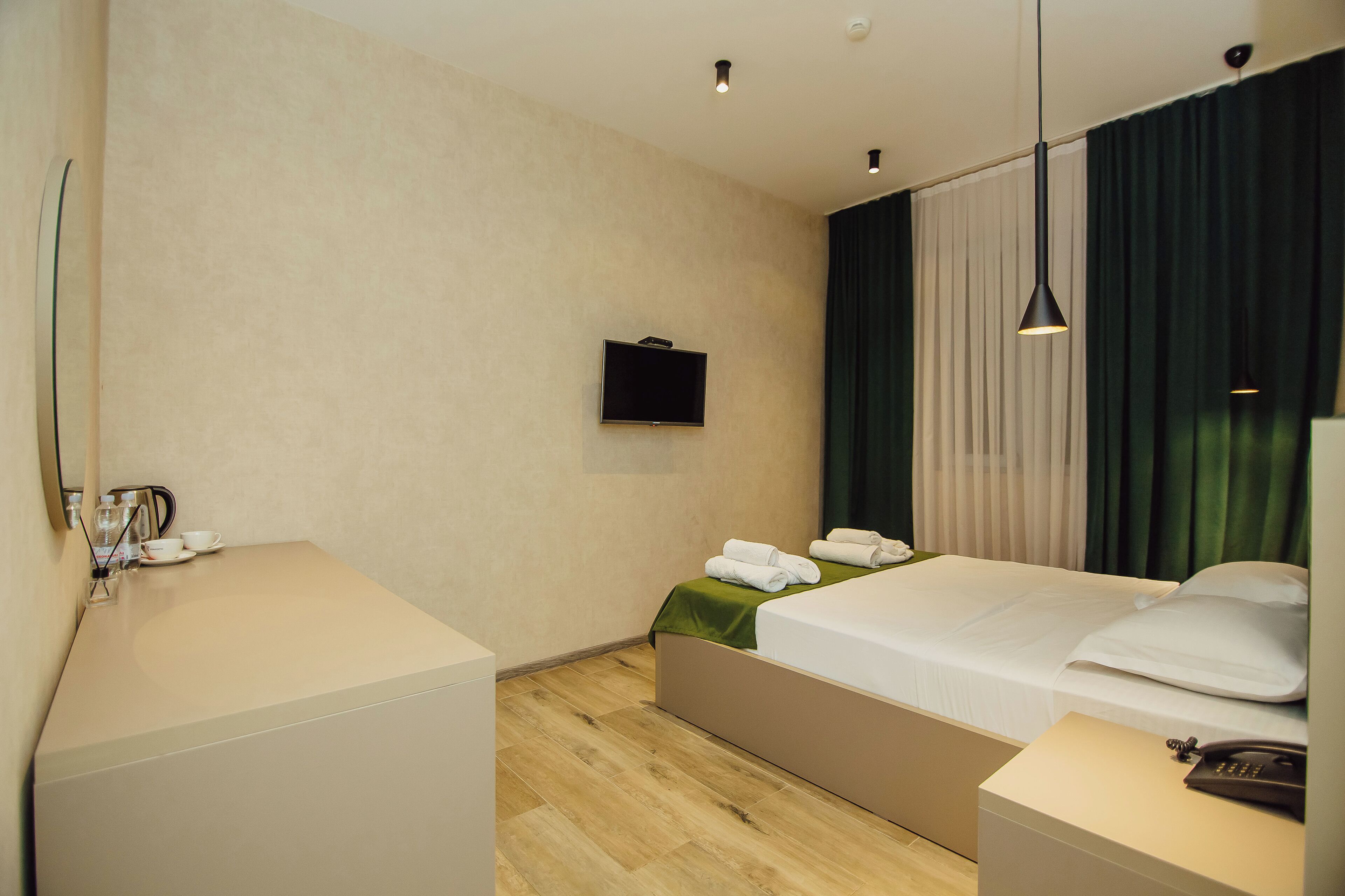 Una habitación de hotel con una cama, una mesita de noche y un televisor montado en la pared.