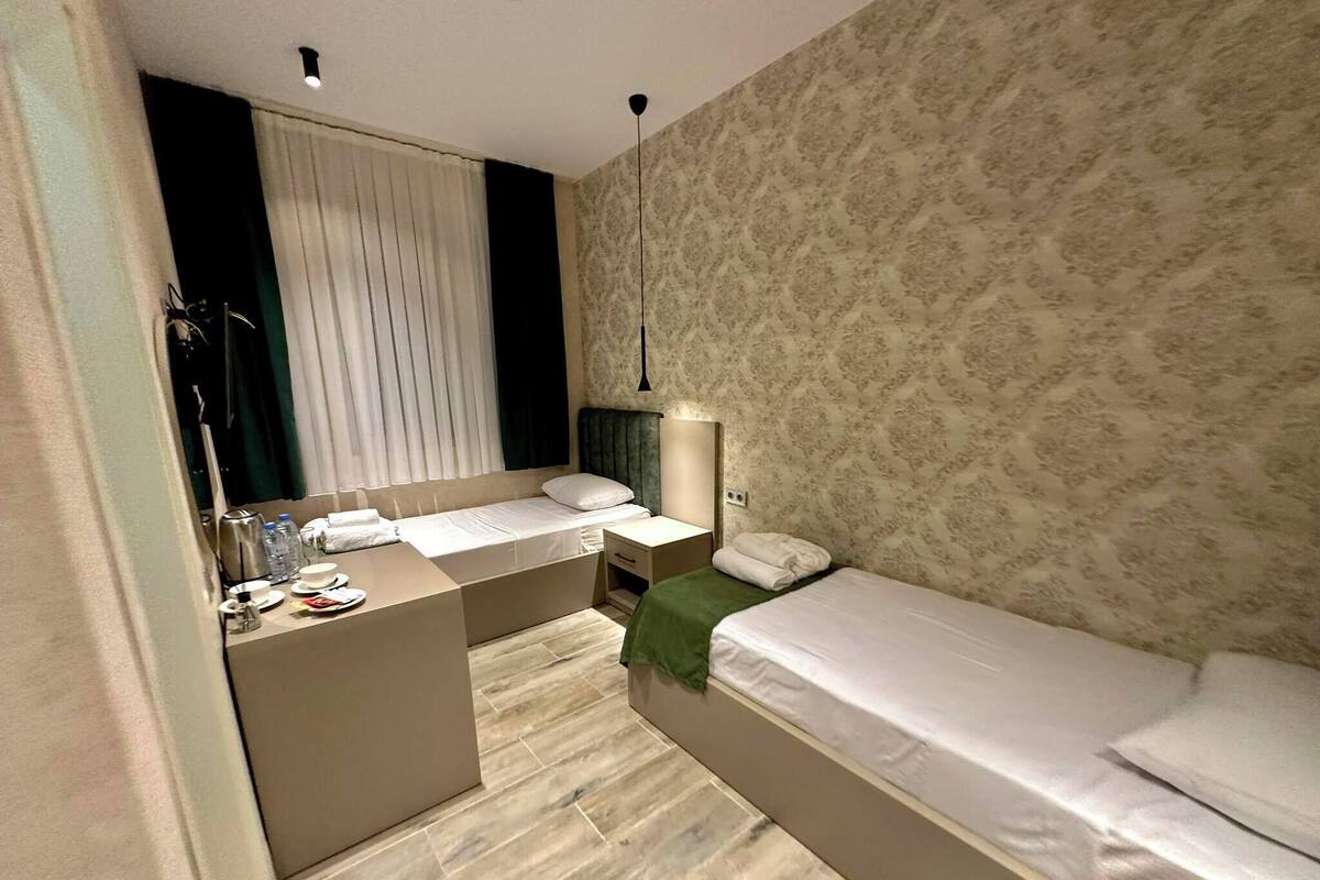 A compact hotel room with a bed, a desk, and a small seating area.