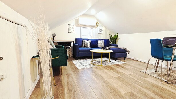 Ein stilvolles Wohnzimmer mit einem blauen Sofa, einem grünen Sessel und einem kleinen runden Tisch.