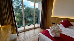 A hotel room with a large sliding glass door leading to a balcony with a view of trees. - ZAAD SUITE (Meenachil)