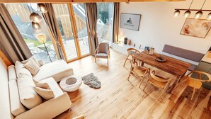 Un espace de vie moderne à aire ouverte, doté d’un plancher en bois, d’un canapé, d’une table à manger et d’un escalier menant à un niveau supérieur.