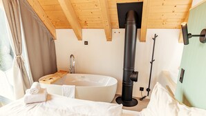 Une salle de bain moderne avec une grande baignoire, un plafond en bois et un tuyau noir.