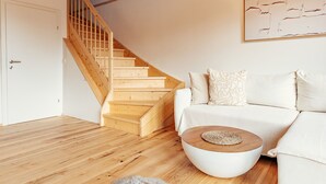 Un salon moderne avec un escalier en bois, un canapé blanc et une table basse ronde.