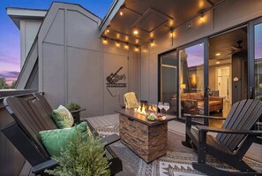 An outdoor patio area with a stone fire feature, seating, and a view into the interior.