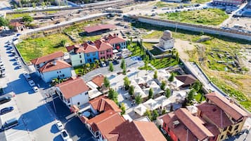 An aerial view of a town with a mix of residential buildings, a central plaza with outdoor seating, and a fortified structure.